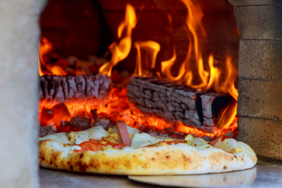 Gourmet Pizza Coming Out Wood Fired Pizza Oven in Restaurant